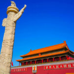 Stone pillar in front of Tiananmen Gate with a blue sky backdrop