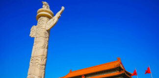 Stone pillar in front of Tiananmen Gate with a blue sky backdrop