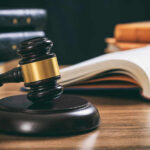 Judge Blinks As Costs Explode Judge's gavel on desk with open law book
