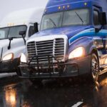 Two semi trucks driving side by side on a wet highway