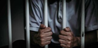 person gripping prison bars