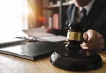Funeral Director Accused Of Shocking Fraud Judge's gavel on desk with person reading documents in background