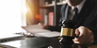 Funeral Director Accused Of Shocking Fraud Judge's gavel on desk with person reading documents in background