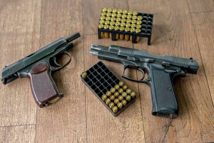 Two handguns and boxes of ammunition on a wooden floor