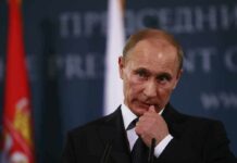 Shock Death Scrambles Russia Sanctions Push man in suit at podium touching his face