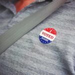 I voted sticker on a gray shirt under a seat belt