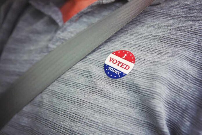 shutterstock_1156344568 I voted sticker on a gray shirt under a seat belt