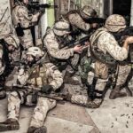 soldiers in camouflage gear take positions inside a damaged building
