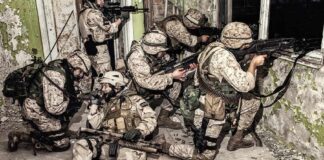soldiers in camouflage gear take positions inside a damaged building