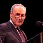 Donor Whisper Exposes Schumer’s Move Elderly man in suit at a podium with microphone