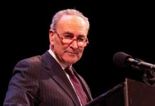 Elderly man in suit at a podium with microphone