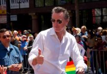 Man in white shirt giving thumbs up at a pride parade