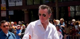 Transparency Fight Exposes Newsom’s Mystery Gaps Man in white shirt giving thumbs up at a pride parade