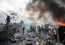 Russia Closes Door On Near-Term Talks A chaotic protest scene with smoke, fire, and people holding flags