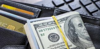 Roll of US hundred-dollar bills on wallet