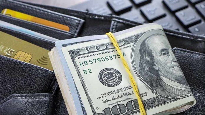 Roll of US hundred-dollar bills on wallet