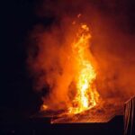 House roof engulfed in flames at night