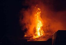 House roof engulfed in flames at night