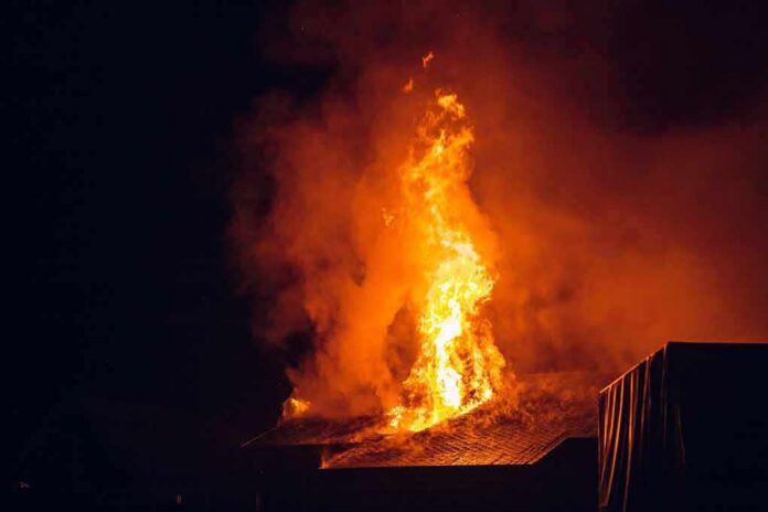 House roof engulfed in flames at night