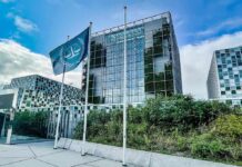 Modern glass office building with blue flag and greenery
