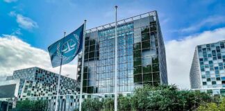 Modern glass office building with blue flag and greenery