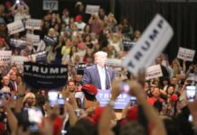 Trump Tests His Grip in South Carolina man at podium addressing a large crowd at a rally