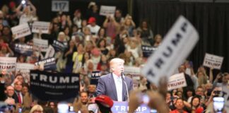Trump Tests His Grip in South Carolina man at podium addressing a large crowd at a rally