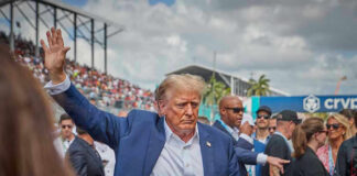 Person in blue suit waving at outdoor event.
