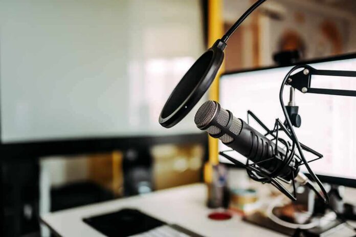 shutterstock_1098006998 Podcast microphone with pop filter on desk