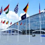 Row of national flags outside a modern glass building