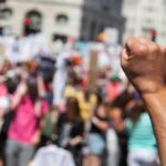 Raised fist in foreground at a crowded street protest