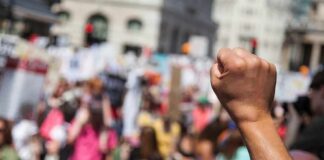 Raised fist in foreground at a crowded street protest
