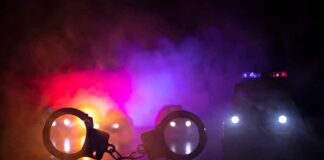 Dinner Run Turns Into Nightmare Handcuffs on a surface with police cars and flashing lights in smoky darkness