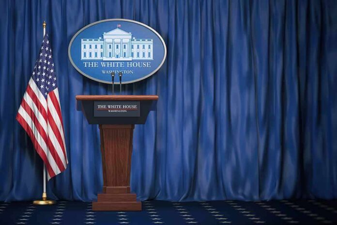 shutterstock_1165119412-2 White House press briefing podium with U.S. flag and blue curtain