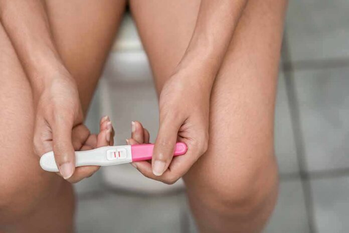 shutterstock_1214504233 Hands holding a home pregnancy test showing two lines