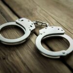 Metal handcuffs on wooden surface