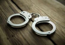 Metal handcuffs on wooden surface
