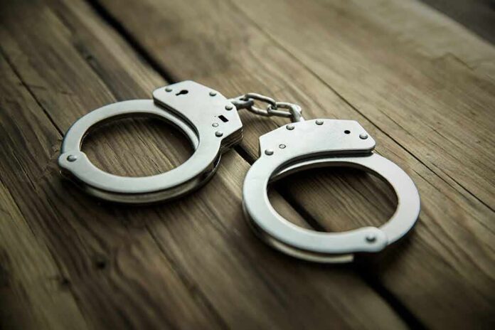 Metal handcuffs on wooden surface
