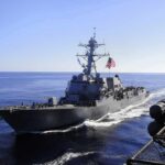 Another Dangerous Clash Erupts Near Hormuz naval destroyer sailing at sea with flag flying