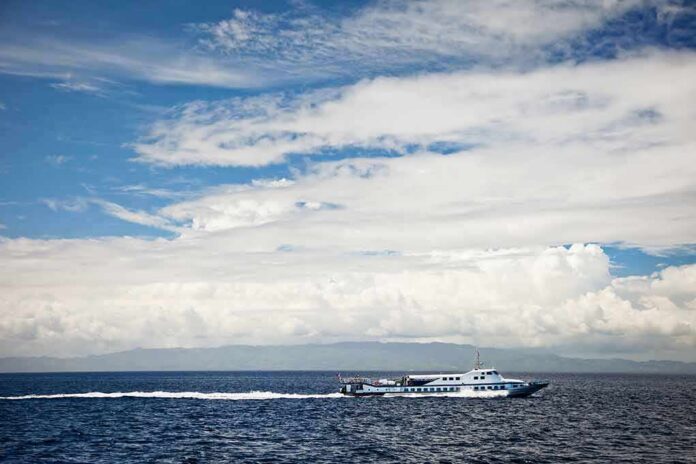 shutterstock_129186611 White passenger boat cruising on open sea under cloudy sky