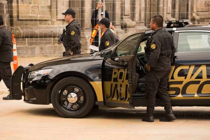 shutterstock_1493728583 Police officers beside a black patrol car with open door