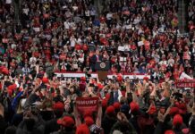 Speaker at podium addressing large crowd in arena