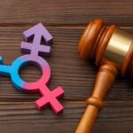 Wooden gavel beside multicolored transgender symbol