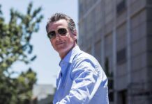 DOJ Subpoenas Rock Newsom’s Travel Tab man in sunglasses wearing a light blue shirt outdoors
