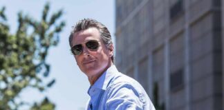 man in sunglasses wearing a light blue shirt outdoors