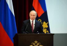 speaker at podium with flags in background