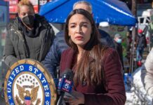 Woman speaking at outdoor press event with microphones and seal