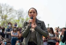 woman speaking into a microphone at an outdoor rally