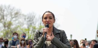 woman speaking into a microphone at an outdoor rally