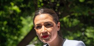 Dems Bench AOC In Swing Seats woman speaking at an outdoor microphone